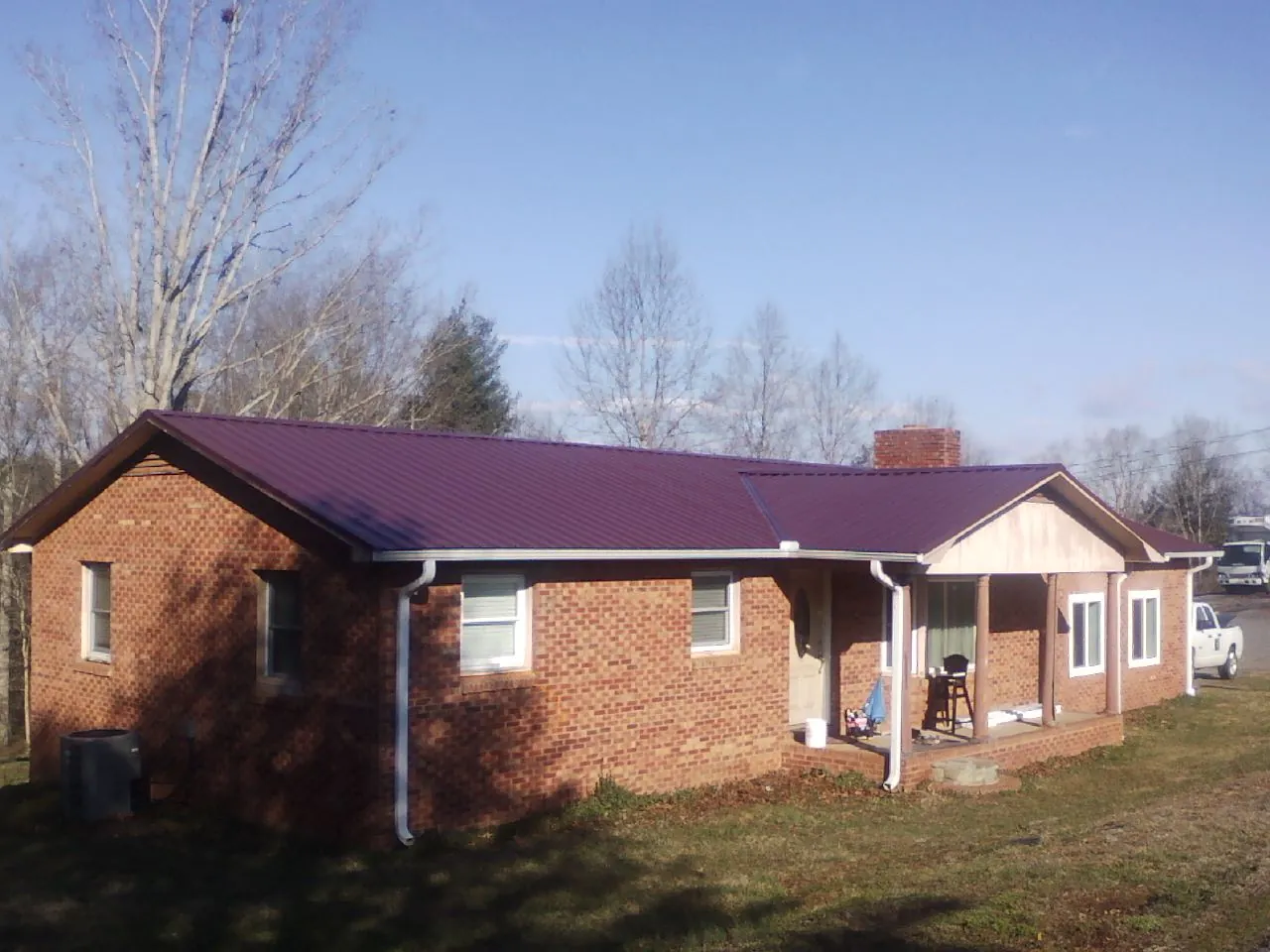 Burgundy metal roof on a brick ranch home with a new addition in Cougar