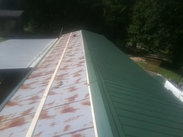 Old rusted panels beside newly installed green metal roofing — Wind Damage Roof Repair by Roofing Brothers in Cougar