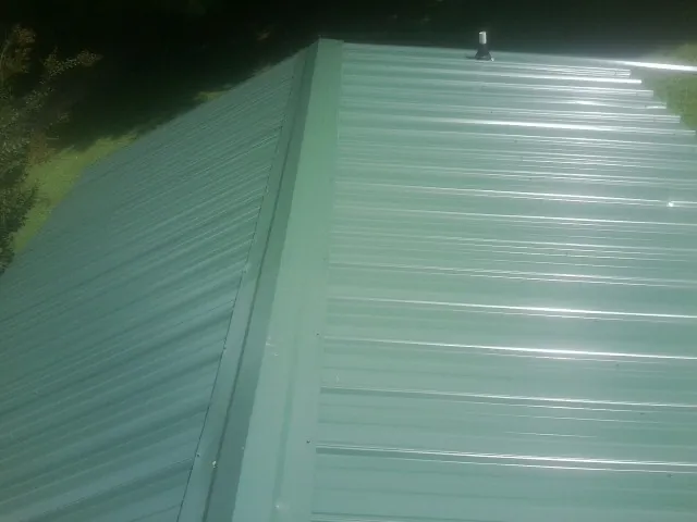 New green metal panels meeting at the ridge of a roof — Flat Roof Repair work by our crew in Cougar