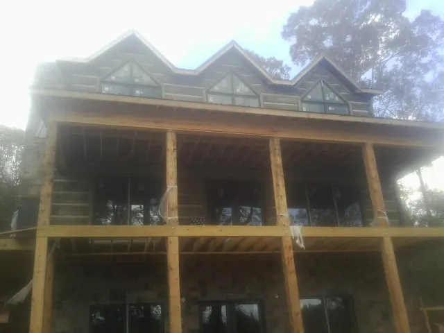 Dormers and porch framing on a large log home under construction — Roof Coating work by our crew in Cougar