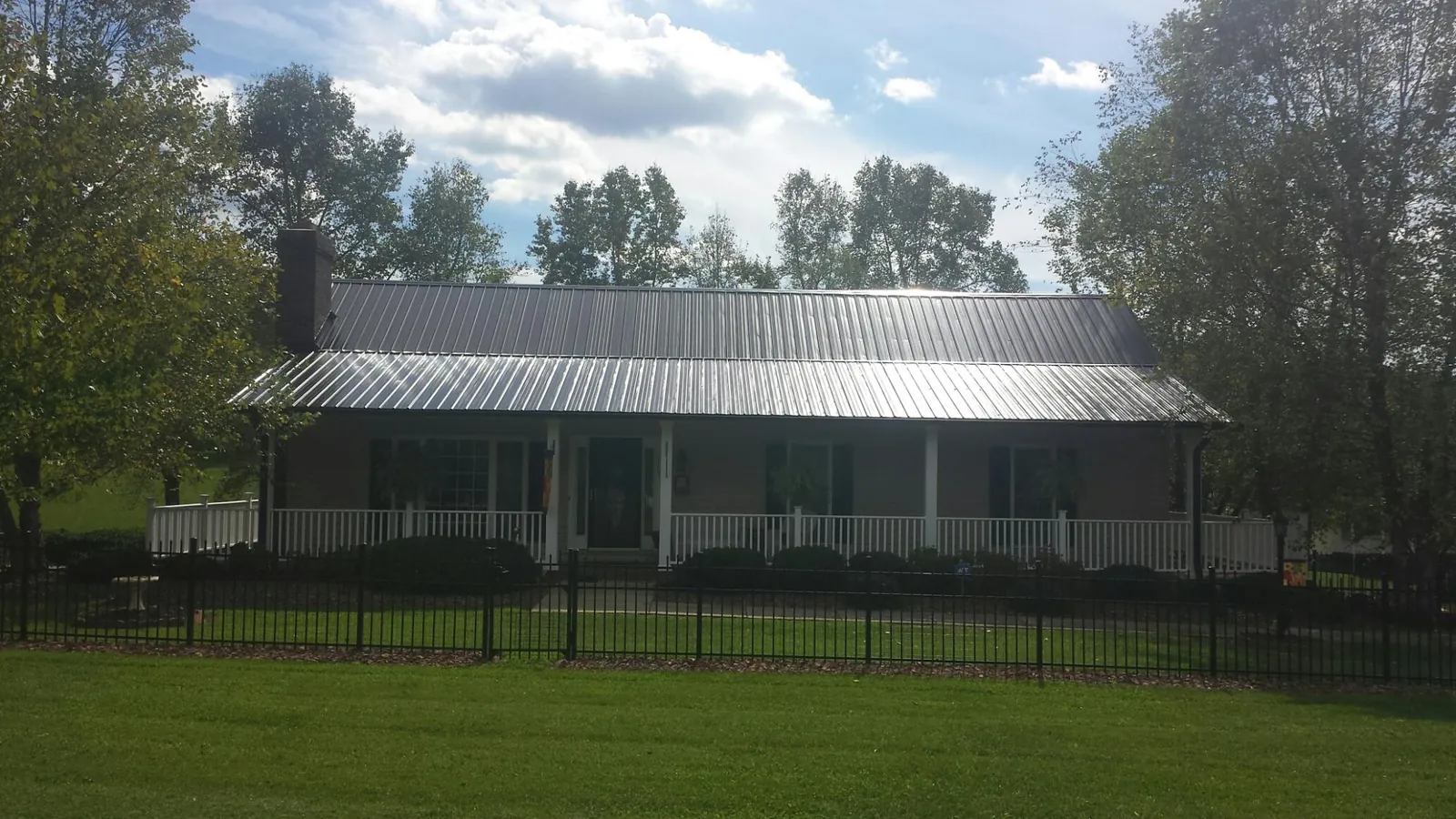 Gray metal roof on a brick ranch with a full width front porch — Gutter Guard Installation work by our crew in Cougar