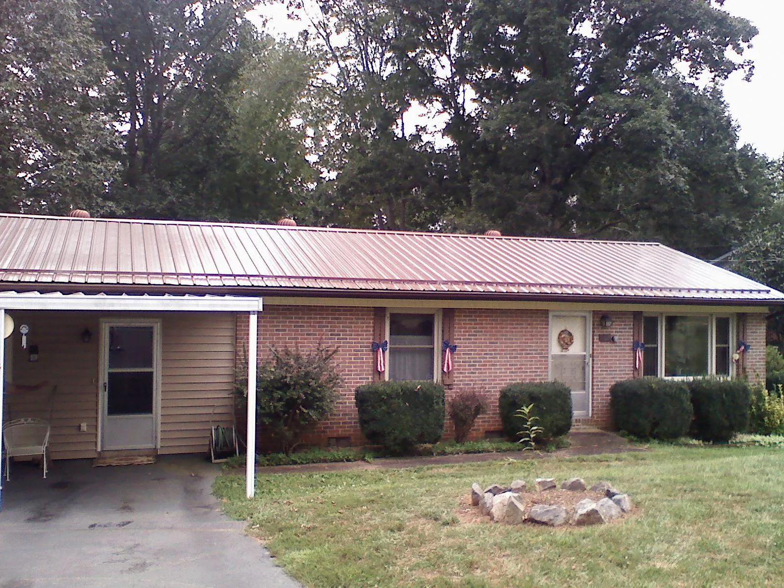 Bronze metal roof and carport on a brick ranch home — Roof Repair work by our crew in Cougar