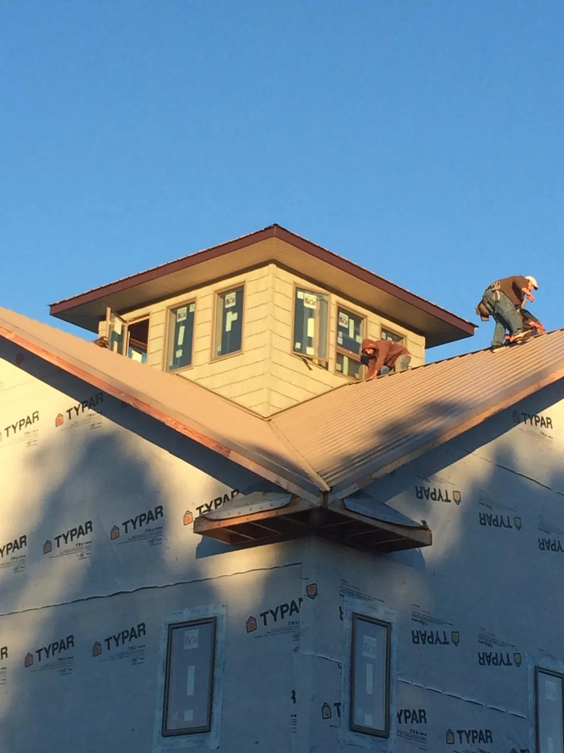 Roofers working around a rooftop cupola on a new metal roof at sunset — Roof Waterproofing in Cougar by Roofing Brothers